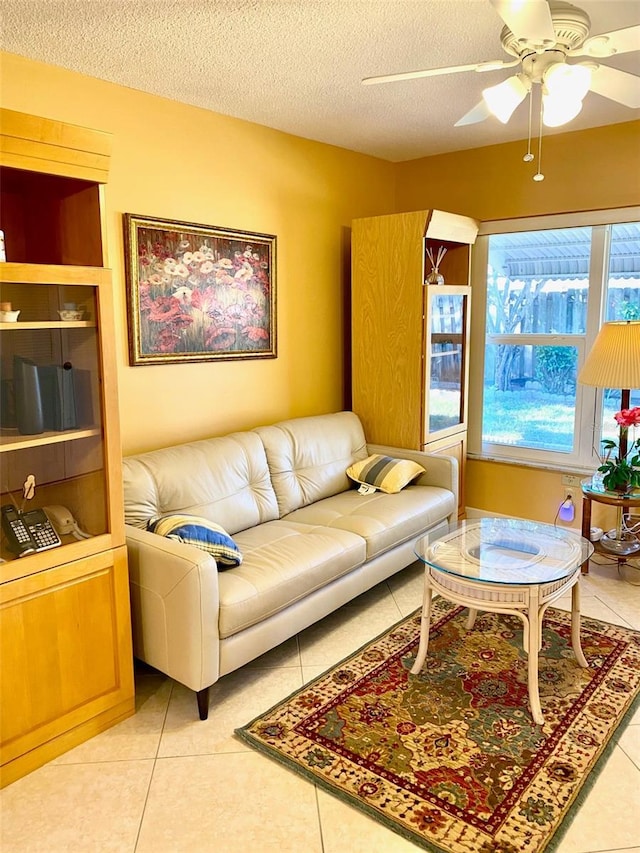 living area featuring a textured ceiling, tile patterned flooring, and a ceiling fan