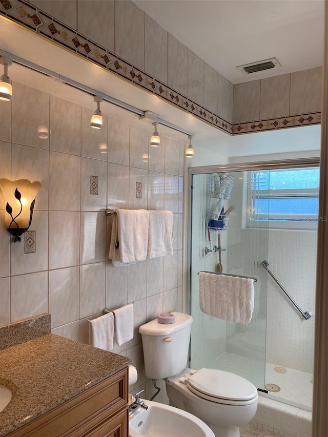 full bath featuring a stall shower, visible vents, toilet, a bidet, and tile walls