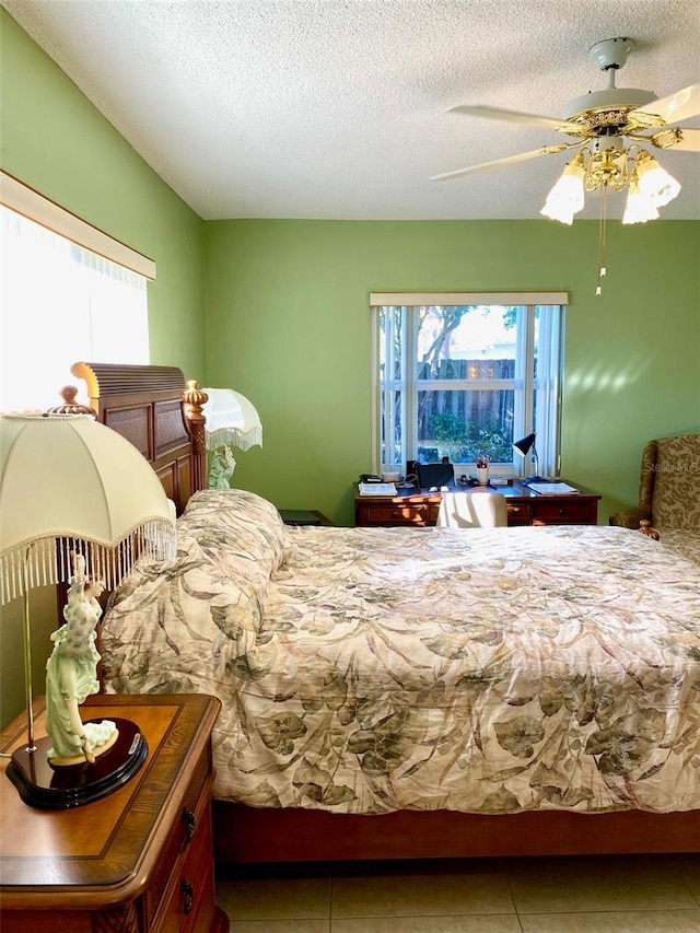 bedroom with a ceiling fan, a textured ceiling, and tile patterned floors