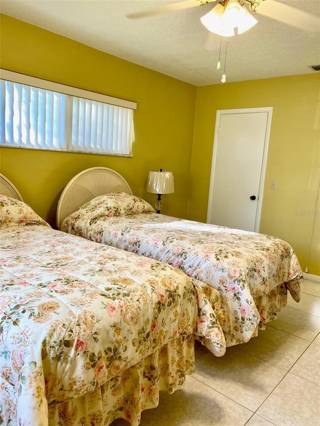 bedroom with light tile patterned floors, a textured ceiling, and a ceiling fan