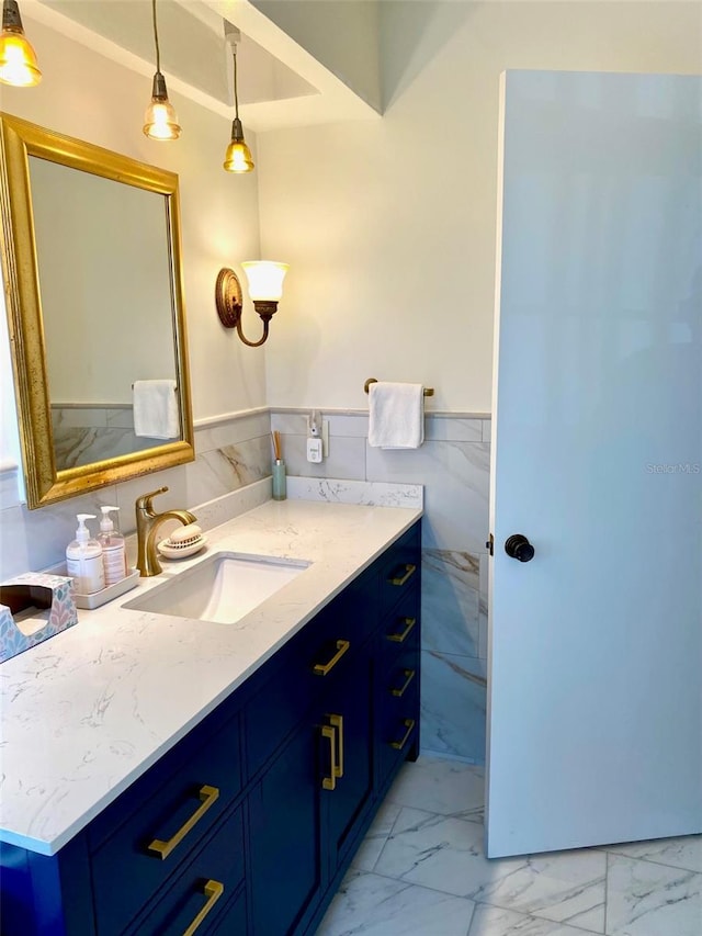 bathroom with marble finish floor, tile walls, a wainscoted wall, and vanity