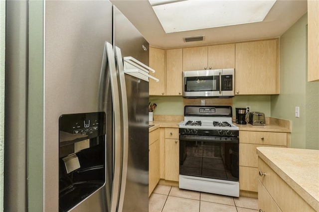 kitchen with light tile patterned floors, visible vents, stainless steel appliances, light countertops, and light brown cabinetry