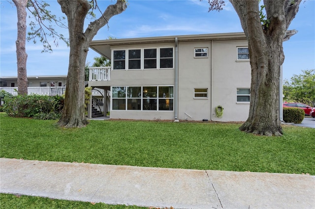 rear view of property featuring stairs, a yard, a wooden deck, and stucco siding