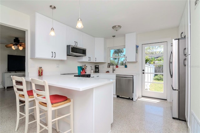 kitchen featuring visible vents, light speckled floor, appliances with stainless steel finishes, a peninsula, and white cabinets