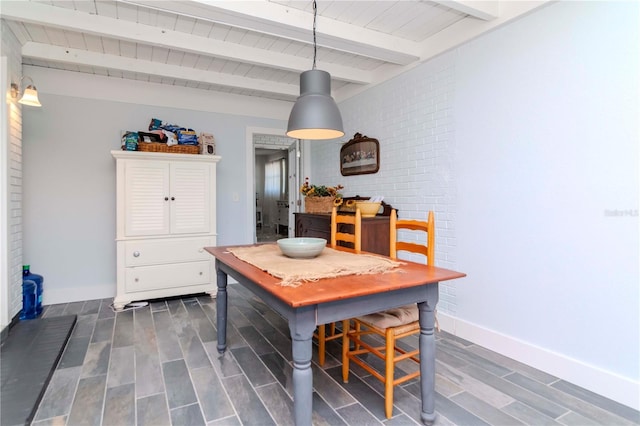 dining area with wood finish floors, beamed ceiling, baseboards, and brick wall