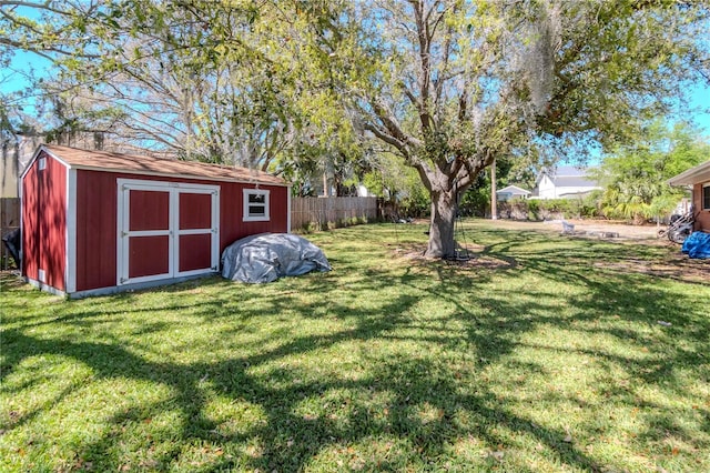 view of yard featuring a storage unit, an outbuilding, and fence