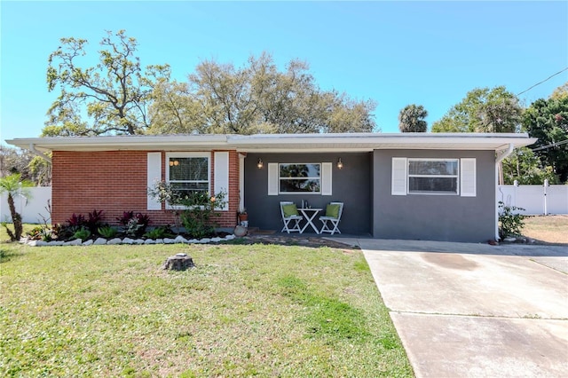 ranch-style home with a front yard, fence, brick siding, and stucco siding