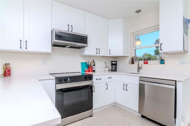 kitchen with a sink, appliances with stainless steel finishes, light countertops, and white cabinetry