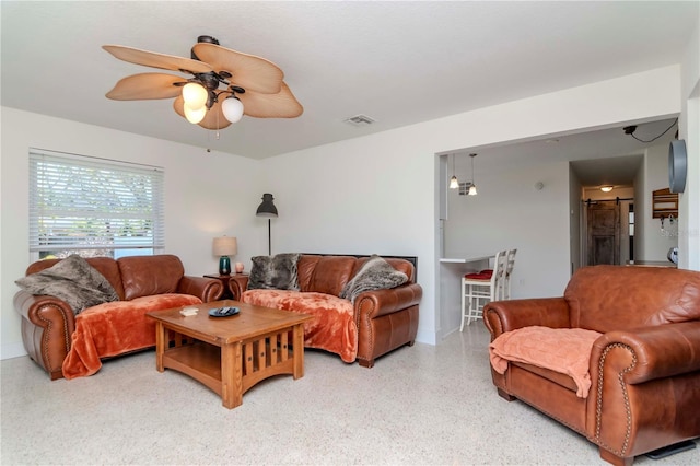 living area featuring visible vents, light speckled floor, and ceiling fan