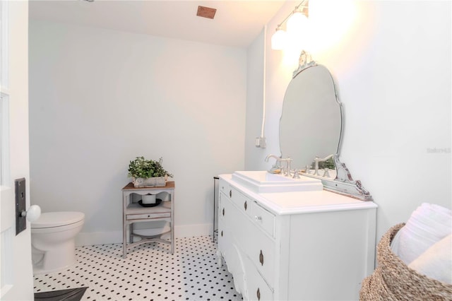 bathroom with toilet, vanity, and baseboards