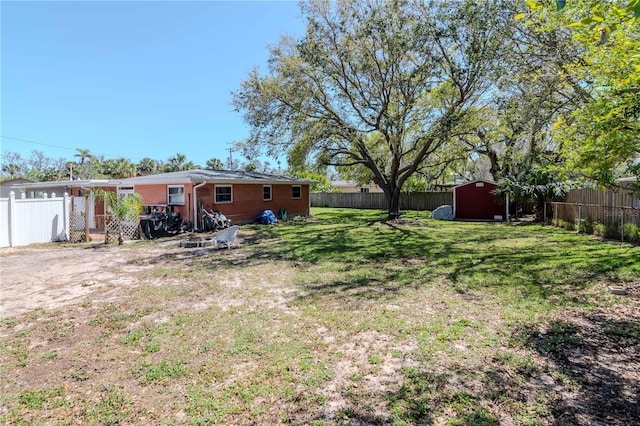 view of yard featuring an outbuilding, a fenced backyard, and a shed