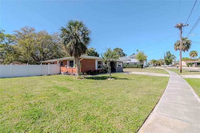 view of front of home featuring fence, brick siding, and a front yard