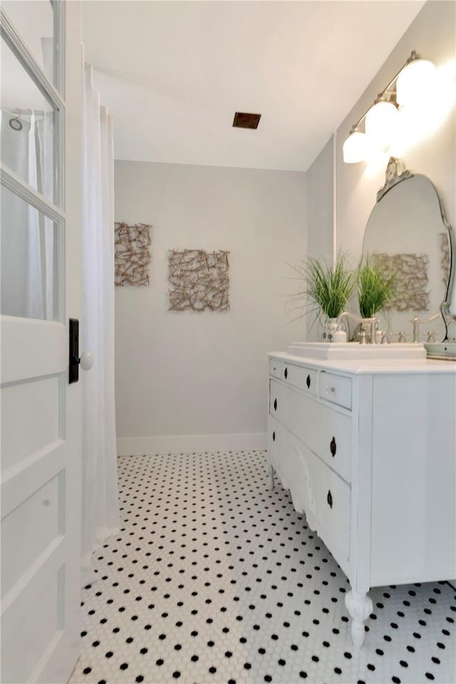 bathroom with double vanity and baseboards