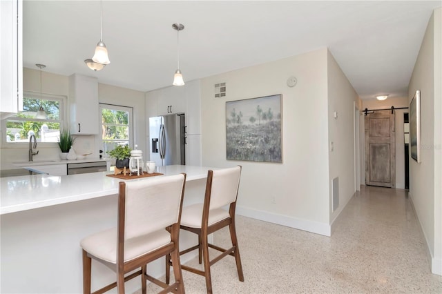 kitchen with light countertops, stainless steel appliances, a sink, and a kitchen bar