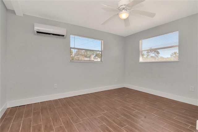 empty room with a ceiling fan, wood finished floors, baseboards, and a wall mounted AC