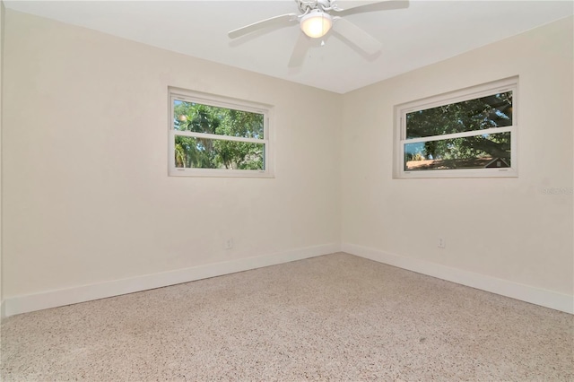 unfurnished room with baseboards, speckled floor, and a ceiling fan