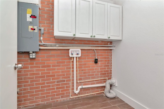 laundry room with electric panel, electric dryer hookup, cabinet space, and wood finished floors
