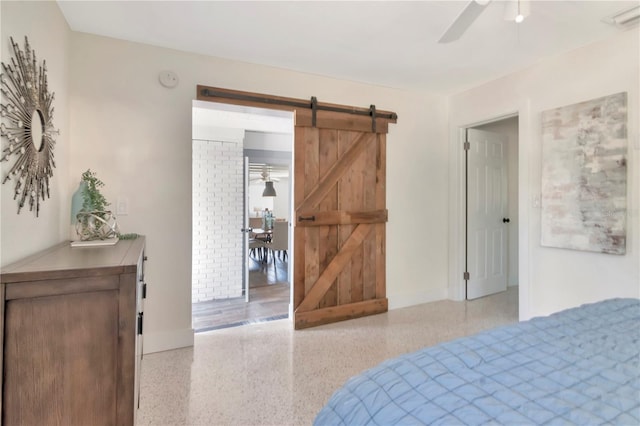 bedroom featuring a ceiling fan, a barn door, baseboards, visible vents, and speckled floor