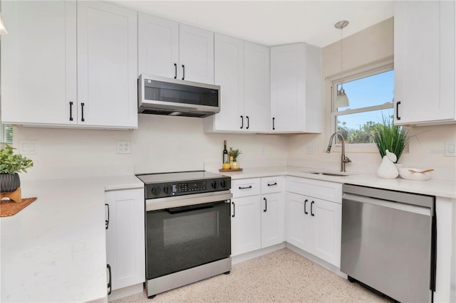 kitchen with a sink, stainless steel appliances, white cabinetry, and light countertops