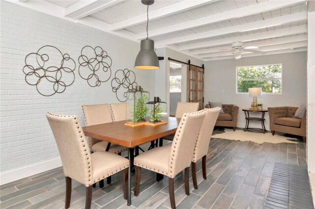 dining room with a barn door, ceiling fan, beamed ceiling, dark wood-style floors, and baseboards