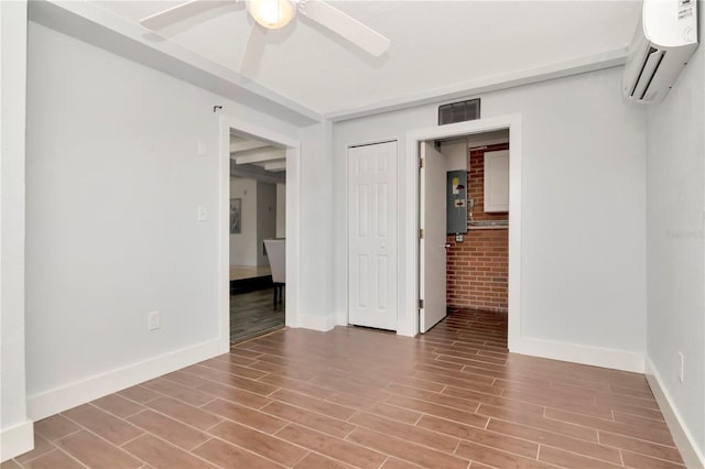 unfurnished bedroom featuring a wall unit AC, baseboards, ceiling fan, visible vents, and wood finished floors