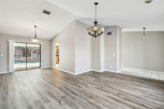 unfurnished room with visible vents, vaulted ceiling, and wood finished floors