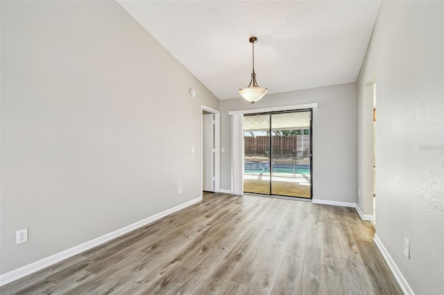 unfurnished room with a textured ceiling, wood finished floors, and baseboards