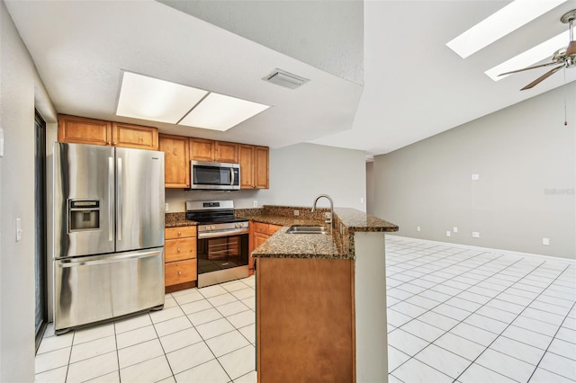 kitchen with light tile patterned floors, stainless steel appliances, a peninsula, a sink, and visible vents