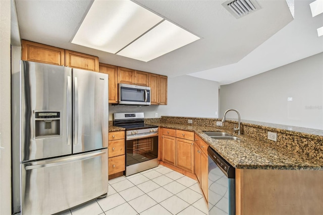 kitchen with light tile patterned floors, a peninsula, a sink, visible vents, and appliances with stainless steel finishes