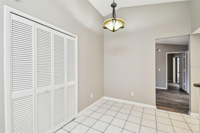 interior space featuring vaulted ceiling, baseboards, and light tile patterned floors