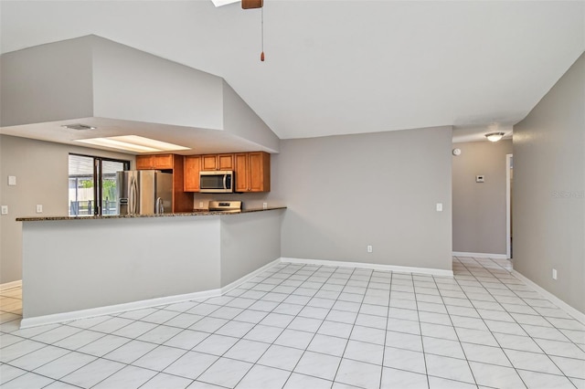 kitchen with a peninsula, baseboards, vaulted ceiling, appliances with stainless steel finishes, and brown cabinetry