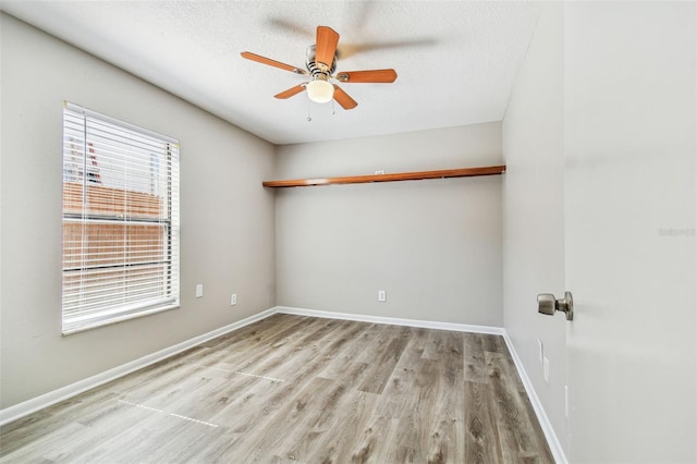 spare room with ceiling fan, a textured ceiling, baseboards, and wood finished floors