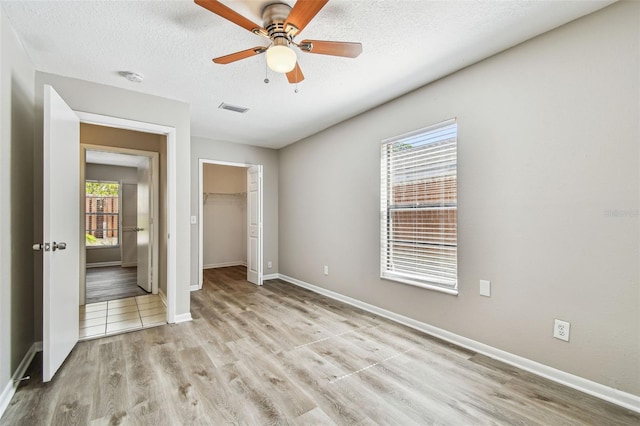 unfurnished bedroom featuring baseboards, visible vents, a textured ceiling, light wood-style floors, and a closet