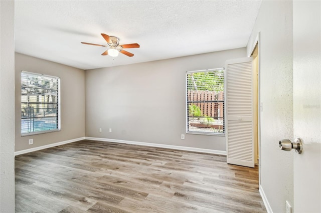 empty room featuring ceiling fan, a textured ceiling, baseboards, and wood finished floors