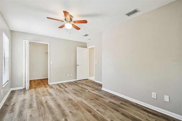 unfurnished bedroom with a closet, visible vents, baseboards, and wood finished floors