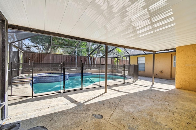 view of pool with a patio area, a pool with connected hot tub, fence, and glass enclosure