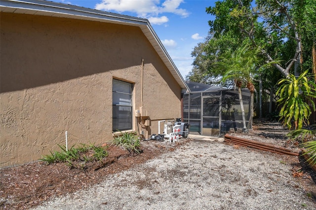 view of home's exterior featuring glass enclosure and stucco siding