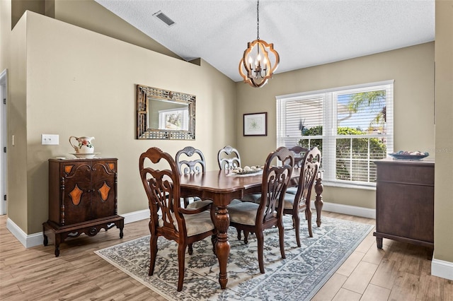 dining space featuring lofted ceiling, a textured ceiling, light wood-style flooring, visible vents, and an inviting chandelier