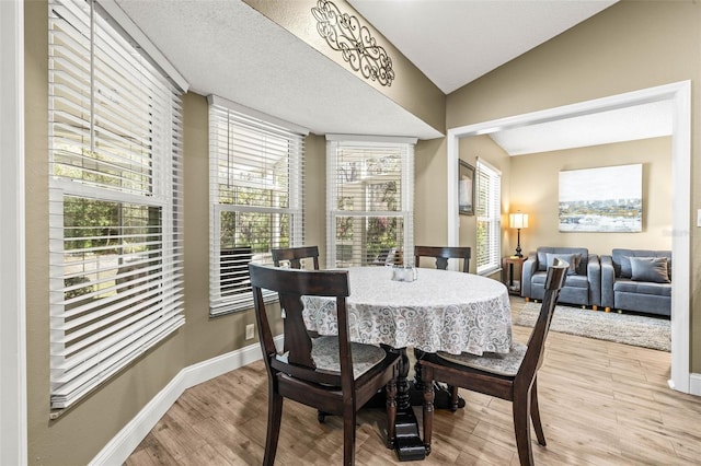 dining space with lofted ceiling, light wood finished floors, and baseboards