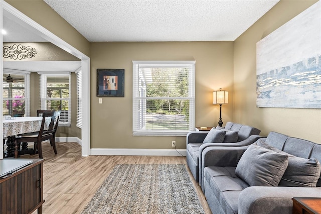 living area with light wood finished floors, baseboards, and a textured ceiling