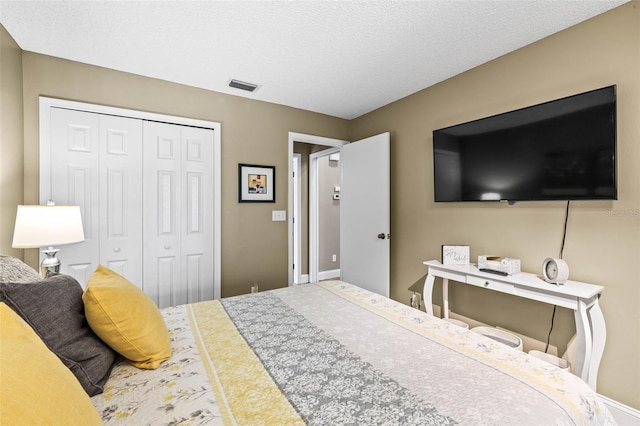 bedroom with a textured ceiling, a closet, and visible vents