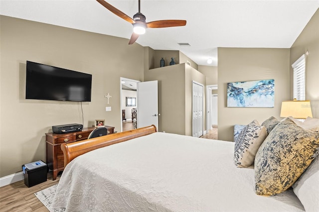 bedroom with light wood finished floors, baseboards, a ceiling fan, vaulted ceiling, and a closet