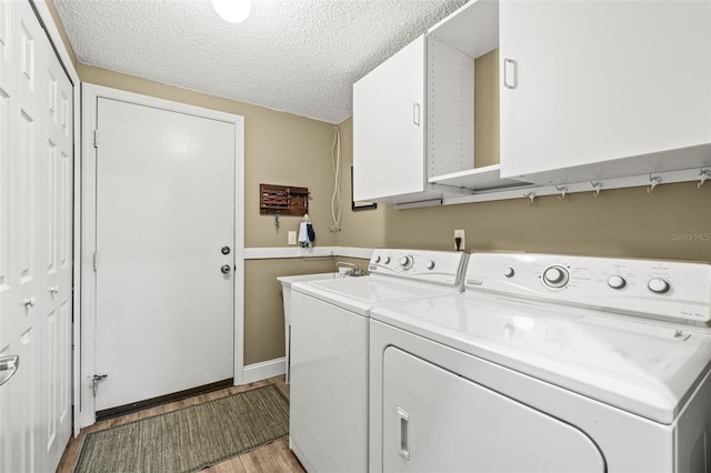 washroom with cabinet space, light wood-style flooring, a textured ceiling, and independent washer and dryer