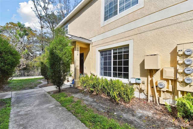 entrance to property with fence and stucco siding