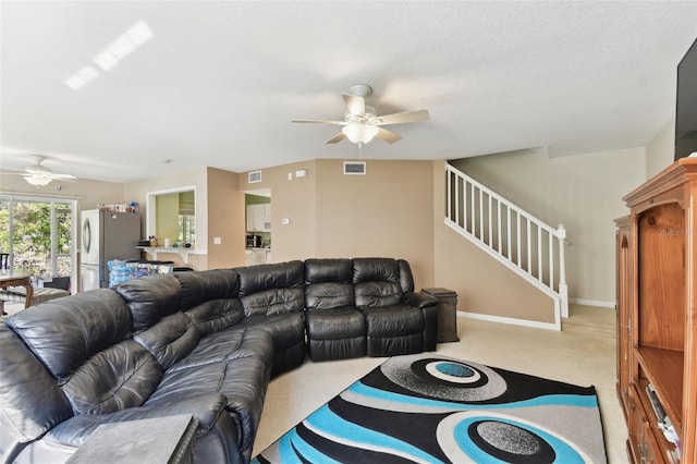 living room featuring carpet, stairs, visible vents, and a ceiling fan