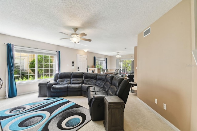 living room with visible vents, light carpet, ceiling fan, a textured ceiling, and baseboards