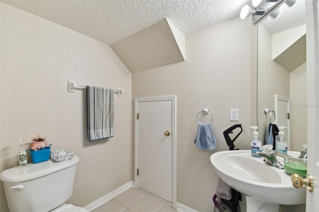 bathroom featuring toilet, a sink, a textured ceiling, tile patterned flooring, and baseboards