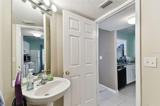 bathroom with tile patterned flooring, visible vents, a sink, and a textured ceiling