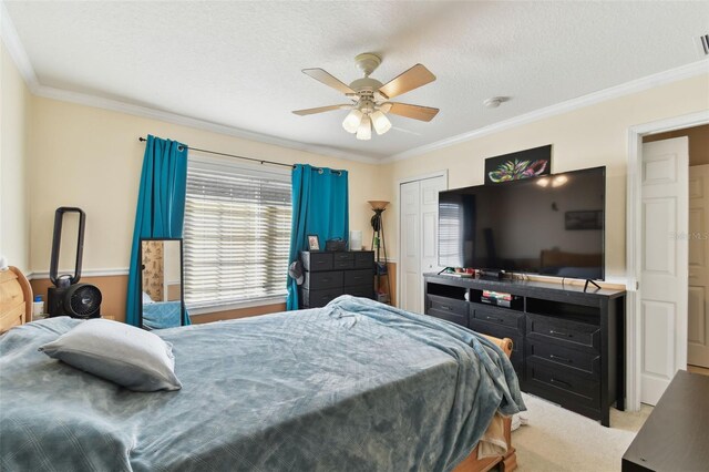 bedroom featuring visible vents, ornamental molding, a ceiling fan, carpet flooring, and a textured ceiling