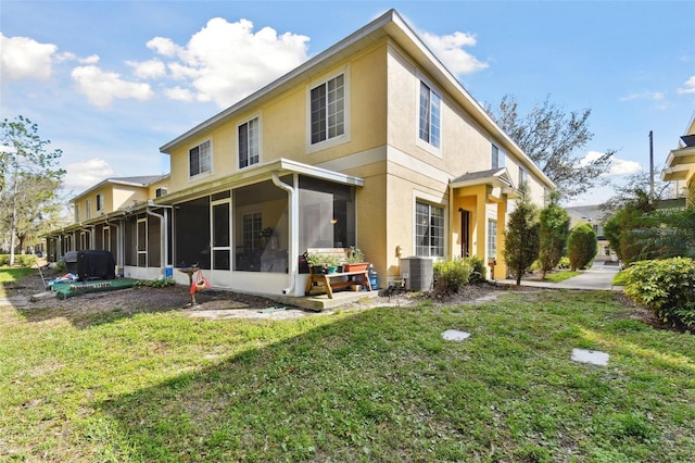 rear view of property with a yard, cooling unit, a sunroom, and stucco siding